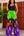 A woman modeling a pair of wide-leg patchwork pants with green, brown, and purple sections featuring white floral patterns, paired with a black tank top.